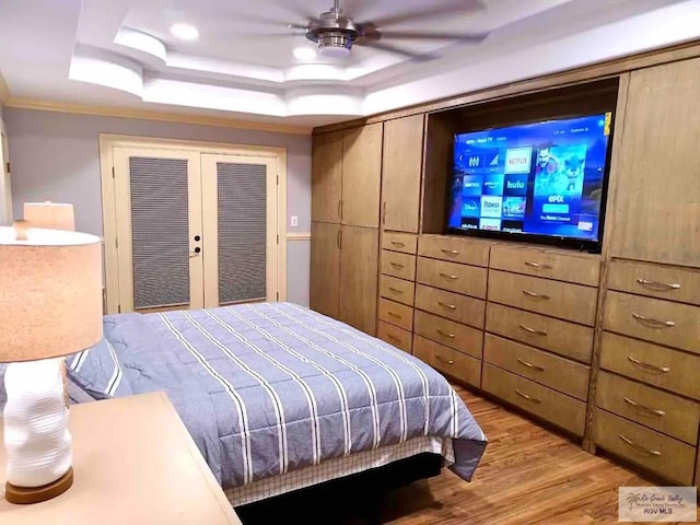 bedroom with hardwood / wood-style flooring, ceiling fan, and a tray ceiling