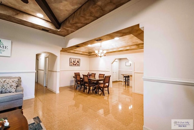 dining space with crown molding, an inviting chandelier, and a raised ceiling