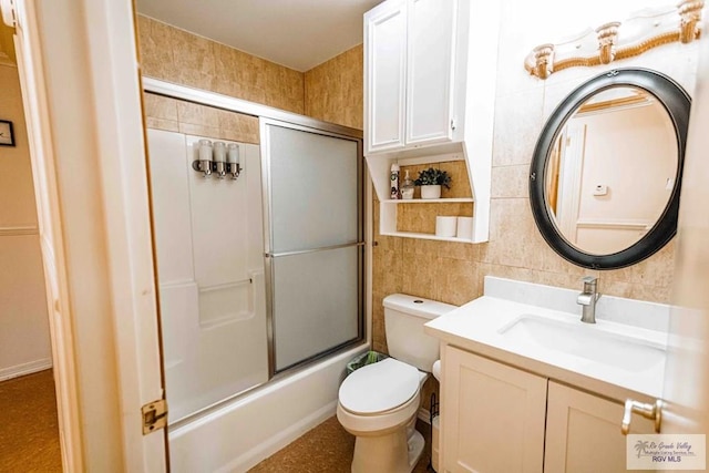 full bathroom featuring toilet, vanity, tile walls, bath / shower combo with glass door, and decorative backsplash