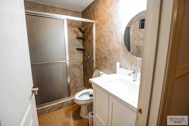 bathroom featuring tile walls, an enclosed shower, vanity, and toilet