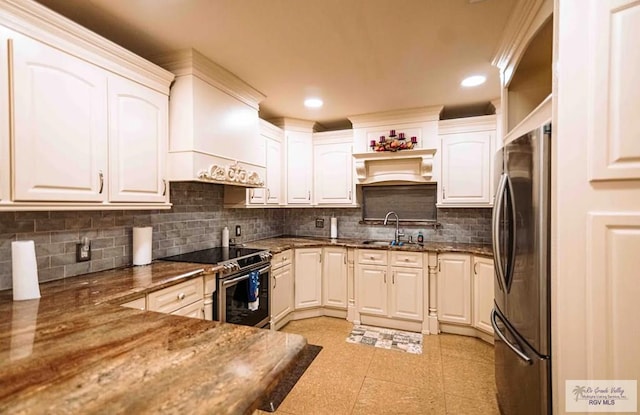 kitchen with stainless steel appliances, dark stone countertops, white cabinetry, and sink