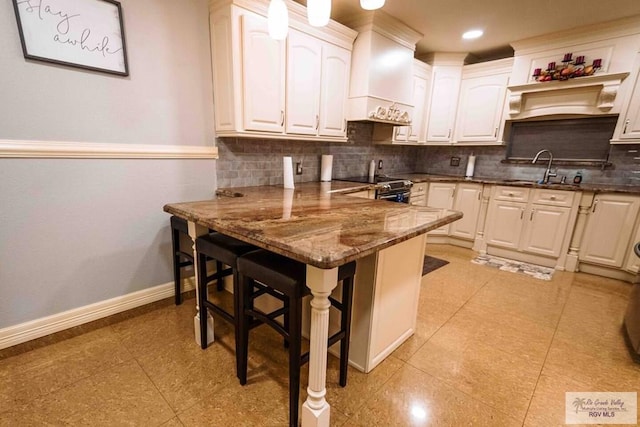 kitchen featuring sink, stainless steel electric stove, a kitchen breakfast bar, custom exhaust hood, and dark stone counters