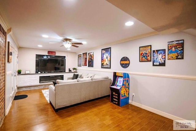 living room with hardwood / wood-style flooring, ceiling fan, and crown molding