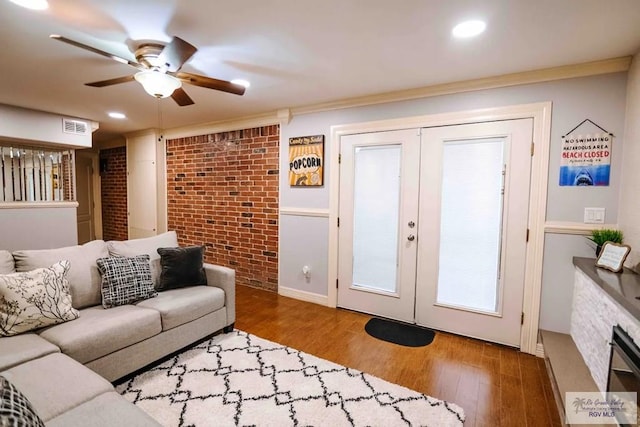 living room featuring ceiling fan, crown molding, brick wall, and hardwood / wood-style flooring