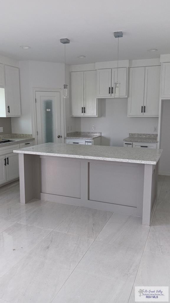 kitchen with a center island, white cabinetry, and hanging light fixtures