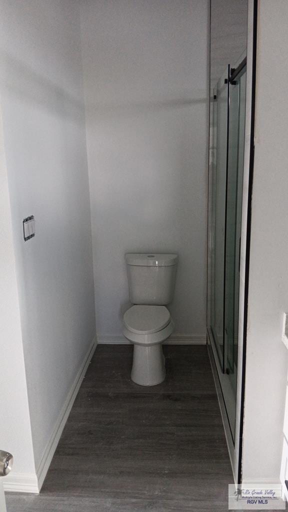 bathroom featuring hardwood / wood-style floors, an enclosed shower, and toilet