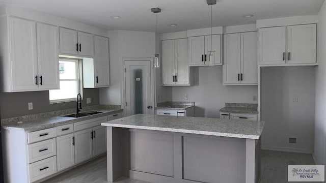 kitchen featuring sink, pendant lighting, white cabinets, light hardwood / wood-style floors, and a kitchen island