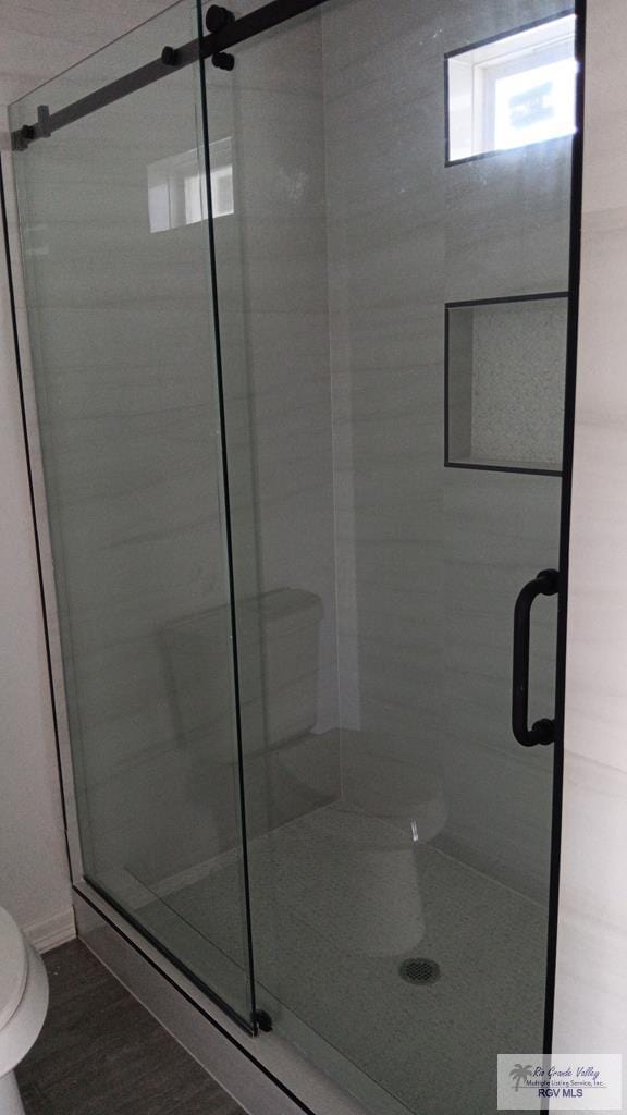 bathroom with toilet and a shower with shower door