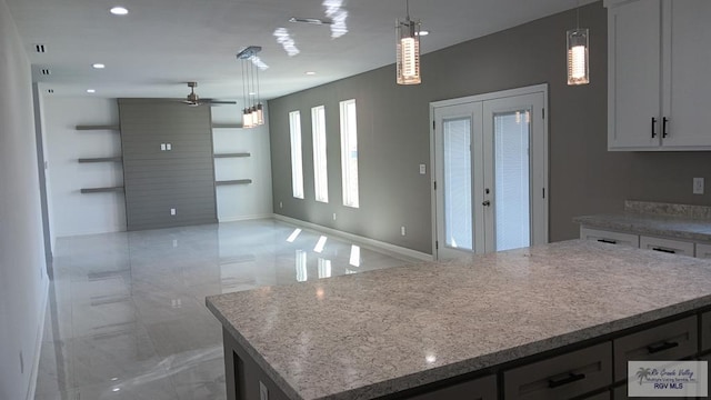 kitchen featuring ceiling fan, a center island, white cabinets, and decorative light fixtures