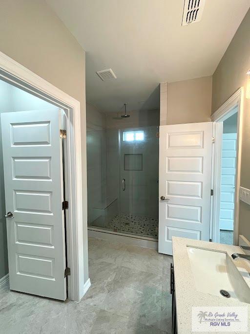 bathroom featuring vanity and a shower with door