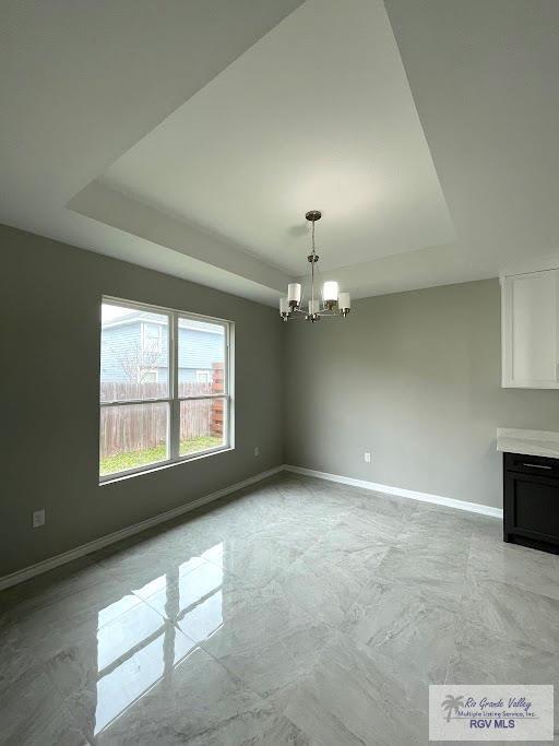 unfurnished dining area featuring a raised ceiling and a notable chandelier