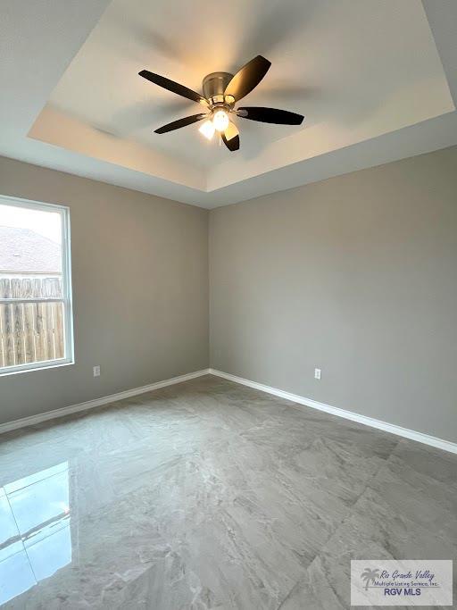 empty room featuring a tray ceiling and ceiling fan