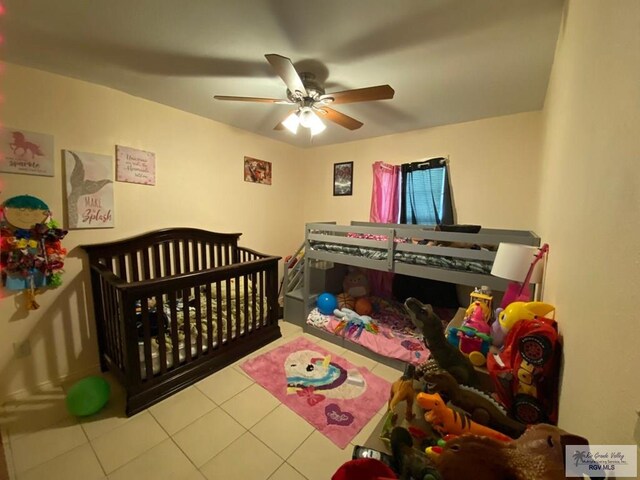 bedroom featuring ceiling fan, a crib, and light tile patterned floors