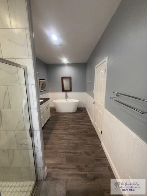 201 Terrace Ln, Harlingen, TX 78550 - bathroom with a stall shower, wood finished floors, a freestanding bath, recessed lighting, and wainscoting
