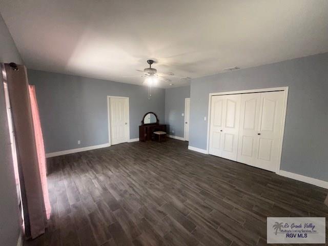 201 Terrace Ln, Harlingen, TX 78550 - unfurnished bedroom featuring dark wood-style floors, baseboards, and ceiling fan