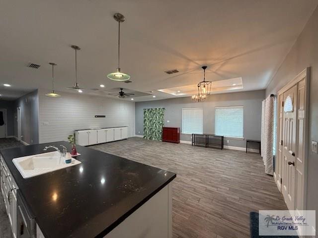 201 Terrace Ln, Harlingen, TX 78550 - kitchen featuring a sink, dark wood-style flooring, a tray ceiling, dark countertops, and a ceiling fan