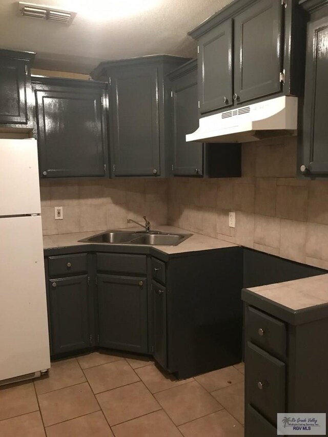 kitchen with backsplash, sink, white fridge, and light tile patterned flooring