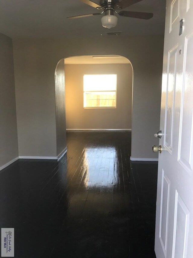 unfurnished room featuring ceiling fan and dark wood-type flooring