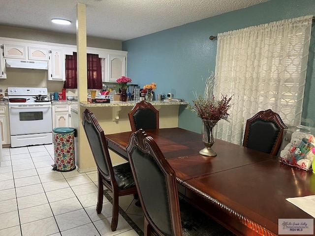 tiled dining space with a textured ceiling