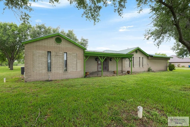 ranch-style home featuring covered porch, metal roof, a front yard, and brick siding