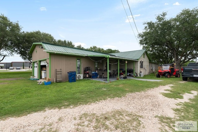 rear view of property featuring a garage, a yard, and metal roof