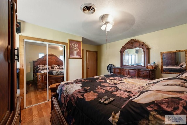 bedroom with visible vents, wood finished floors, ceiling fan, and a closet