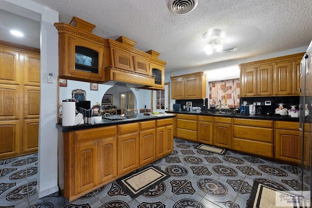 kitchen featuring visible vents, dark countertops, a textured ceiling, and brown cabinets
