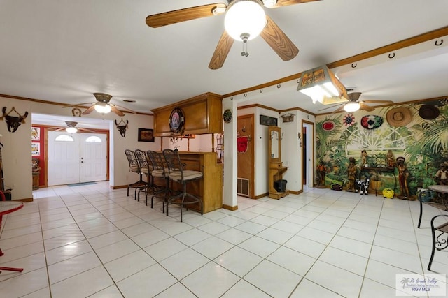 kitchen featuring light tile patterned floors, ceiling fan, baseboards, visible vents, and crown molding