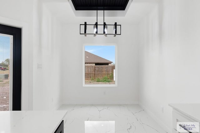 unfurnished dining area featuring a raised ceiling and a chandelier