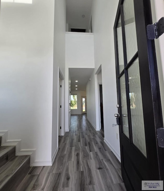 corridor featuring a towering ceiling and dark hardwood / wood-style floors