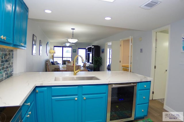 kitchen with blue cabinetry, beverage cooler, and sink