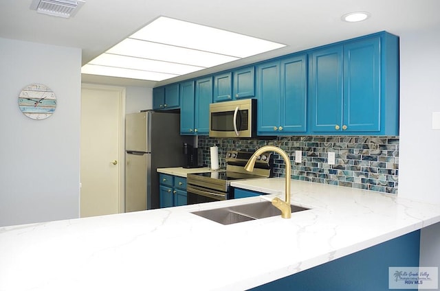 kitchen featuring tasteful backsplash, appliances with stainless steel finishes, blue cabinets, and kitchen peninsula