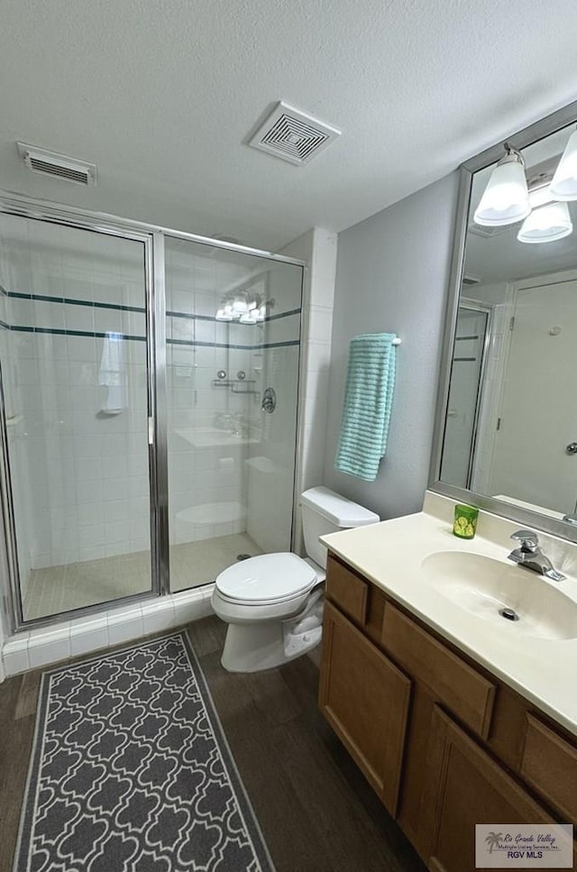 bathroom featuring walk in shower, toilet, a textured ceiling, vanity, and hardwood / wood-style floors