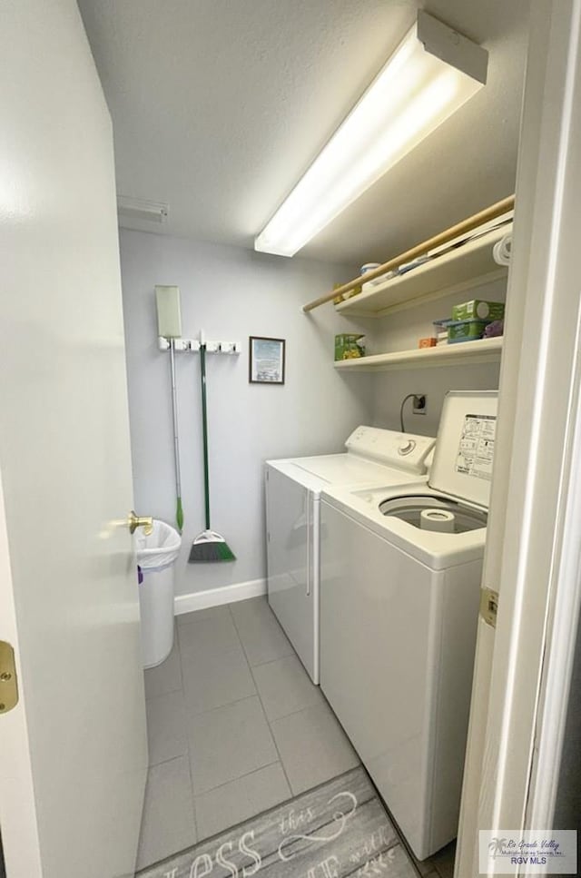 clothes washing area with light tile patterned floors and washing machine and clothes dryer