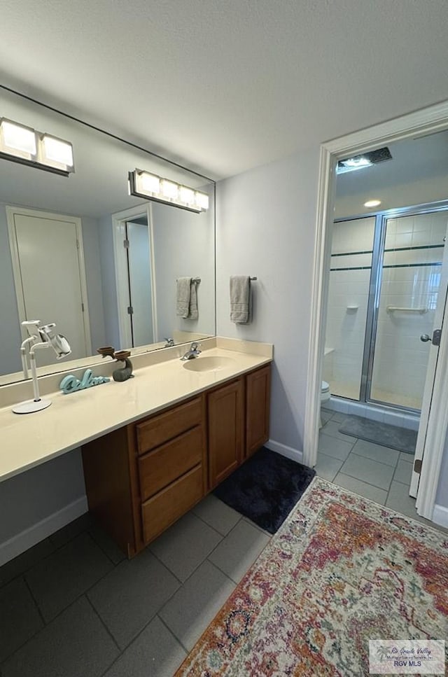 bathroom with tile patterned flooring, vanity, toilet, and walk in shower