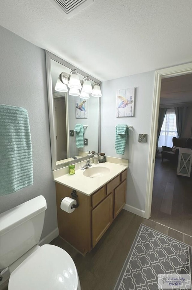 bathroom with wood-type flooring, vanity, a textured ceiling, and toilet