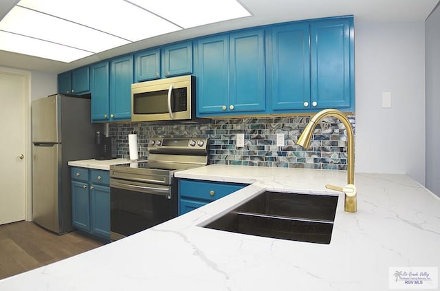 kitchen featuring sink, backsplash, blue cabinetry, and appliances with stainless steel finishes