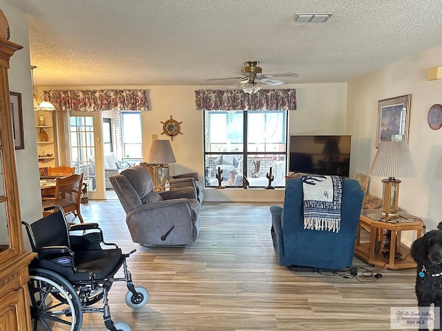 42 Cherokee Dr, Harlingen, TX 78550 - living room featuring a textured ceiling, light wood-style floors, ceiling fan, and healthy amount of natural light