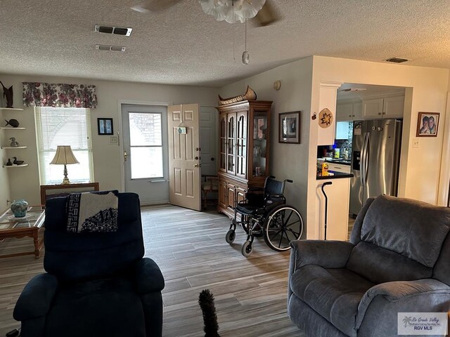 42 Cherokee Dr, Harlingen, TX 78550 - living area featuring light wood-style floors, a ceiling fan, and a textured ceiling
