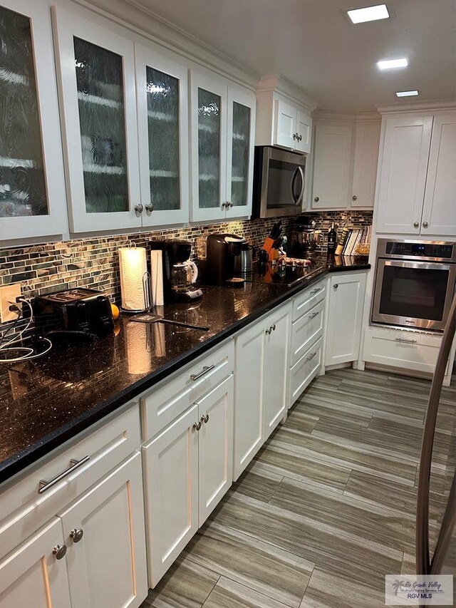 42 Cherokee Dr, Harlingen, TX 78550 - kitchen with appliances with stainless steel finishes, white cabinets, tasteful backsplash, and dark stone countertops