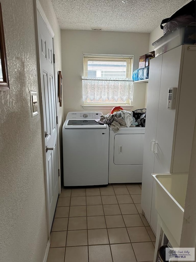 42 Cherokee Dr, Harlingen, TX 78550 - laundry room with washer and clothes dryer, a textured wall, light tile patterned floors, and a textured ceiling