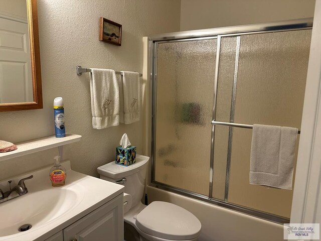 42 Cherokee Dr, Harlingen, TX 78550 - bathroom featuring toilet, enclosed tub / shower combo, a textured wall, and vanity
