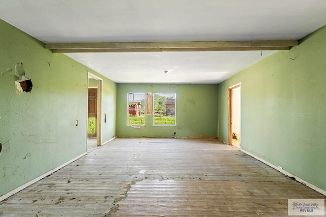 unfurnished room with beam ceiling and light wood-type flooring