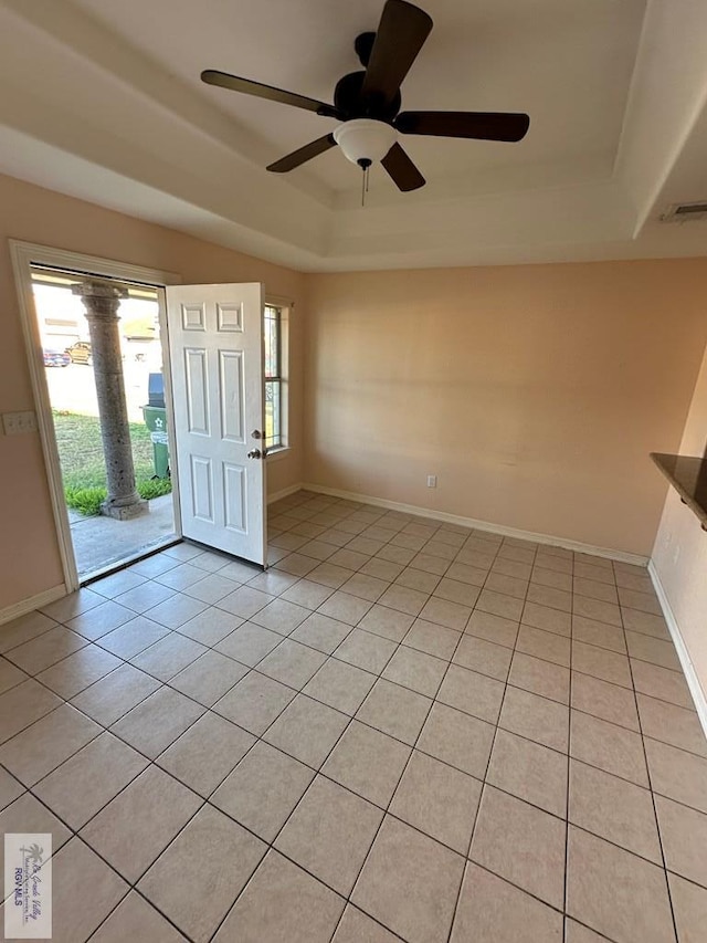 tiled foyer entrance featuring a raised ceiling and ceiling fan