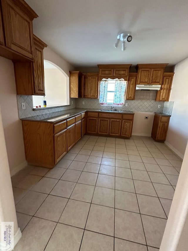 kitchen with backsplash, sink, and light tile patterned flooring