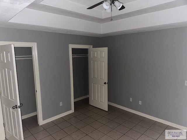 unfurnished bedroom with a raised ceiling, ceiling fan, and light tile patterned floors