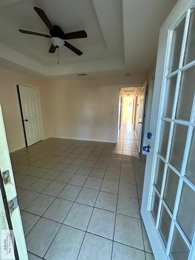 tiled spare room with a raised ceiling and ceiling fan