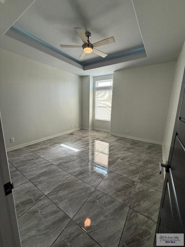 7377 San Andres St, Brownsville, TX 78520 - empty room with a raised ceiling, dark marble finish floors, ceiling fan, and baseboards