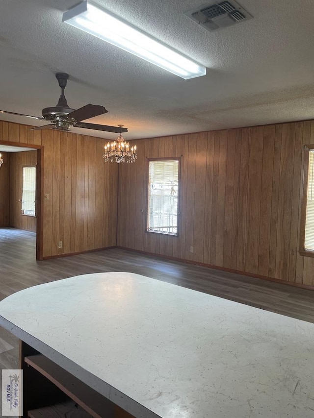 unfurnished room featuring a textured ceiling, dark hardwood / wood-style flooring, and wooden walls