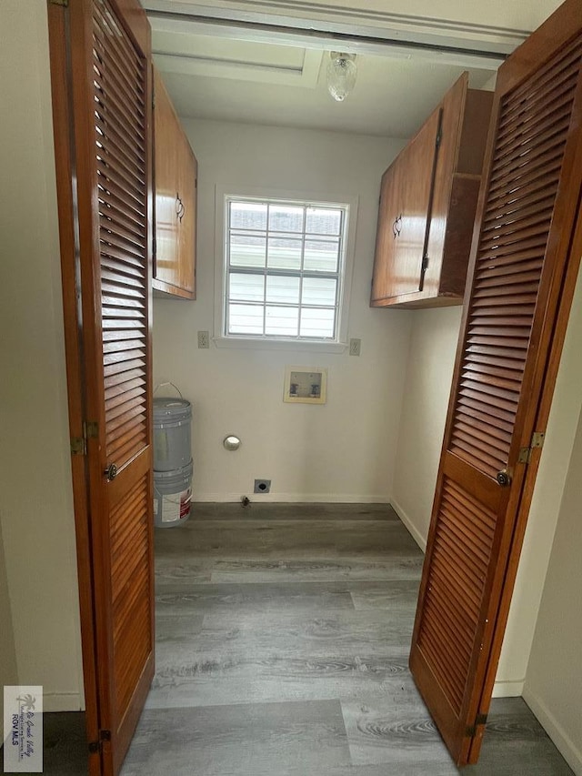 washroom with hookup for an electric dryer, hookup for a washing machine, light wood-type flooring, and cabinets